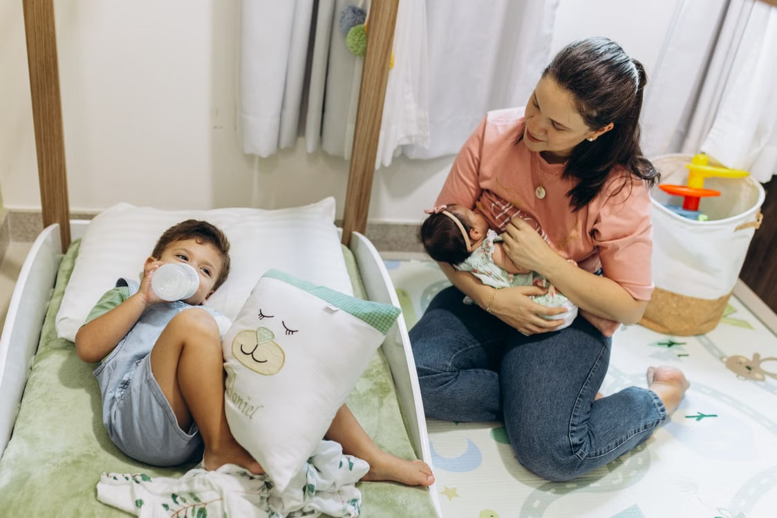 Mother with baby and young child in a warm, nurturing nursery environment