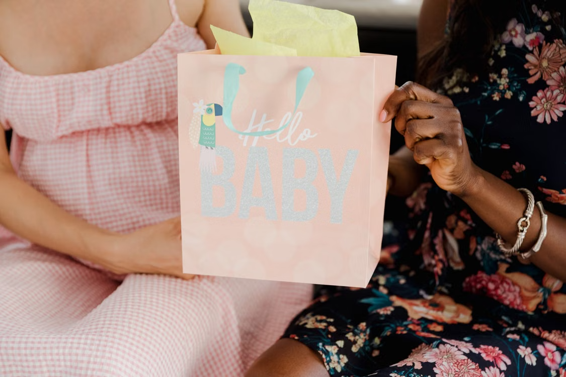 Close-up of a pregnant woman sitting with a baby shower gift bag